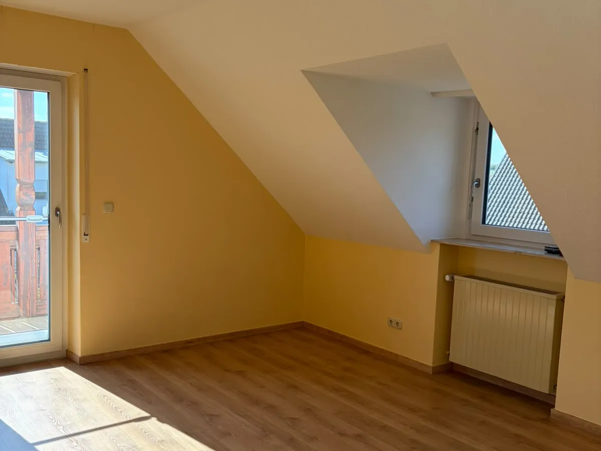 Renoviertes Zimmer unter dem Dach in Großweismannsdorf mit Gaube, Fenstertür, gelb gestrichenen Wänden und neuem Laminat