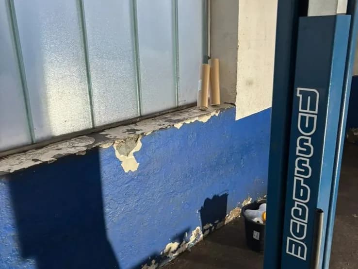 Abgeplatzter blauer Sockelanstrich unter dem Fensterband einer Werkstatt in Fürth-Unterfürberg